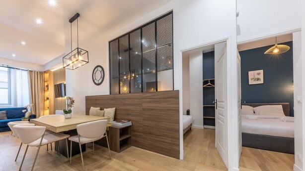 A modern hotel room with a wooden dining table, a sofa, a bed, and a walk-in closet. - Apartment Centre de Paris Sacre Coeur (Paris)
