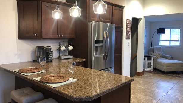 Una cocina con alacenas de madera oscura, un refrigerador de acero inoxidable y una zona para café.