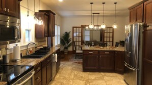 Una cocina moderna con electrodomésticos de acero inoxidable, gabinetes de madera e iluminación colgante.