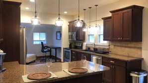 Una cocina moderna con encimeras de granito, electrodomésticos de acero inoxidable e iluminación colgante.