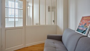 A room with a grey sofa, a white wardrobe, and a window with blinds. - Superb Apartment Arc de Triomphe/ Trocadero (Paris)