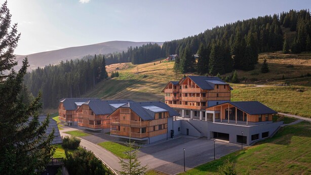 A modern building with multiple wooden structures and a large central building with a sloped roof. - Ferienwohnung mit 2 Schlafzimmern & Sauna (Oberwölz)