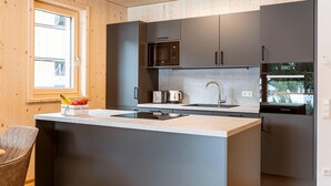 A modern kitchen with a central island, stainless steel appliances, and wooden cabinetry. - Ferienwohnung mit 2 Schlafzimmern & Sauna (Oberwölz)