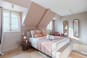 A bedroom with a large bed, a bedside table, a window, and a mirror.