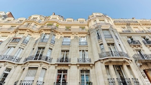 Un immeuble à plusieurs étages, doté de détails architecturaux raffinés, notamment des balcons et des moulures décoratives.