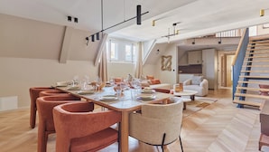 Un vaste espace dédié à la salle à manger, avec une longue table en bois dressée pour le repas, entourée de chaises modernes.