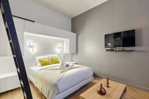 A modern hotel room with a bed, bedside table, and a mounted TV. - Apartment Suite Saint Germain / Rue de Rennes (Paris)