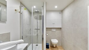 A modern bathroom with a glass-enclosed shower, a white sink, and a toilet. - Suite Saint Germain des Pres Rue de Rennes (Paris)