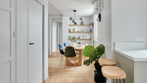 Een moderne keuken met witte kastjes, een houten eettafel en blauwe stoelen.