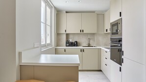 Een moderne keuken met witte kastjes, een inbouwoven en een raam voor natuurlijk licht.