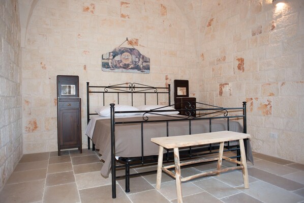 Un dormitorio con cama, mesita de noche y un mueble pequeño.