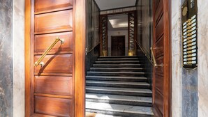 Una escalera de madera con barandilla de latón que lleva a una puerta con cerradura electrónica.