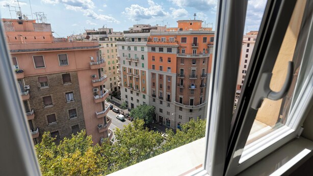 Vista de edificios con balcones, una calle y un cielo despejado.