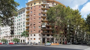Un edificio residencial de varios pisos con balcones, zona de estacionamiento y árboles.