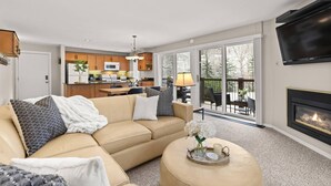 A modern living room with a beige sofa, a flat-screen TV, and a fireplace. - Woodbridge 07A (Snowmass Village)