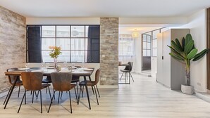 Ein moderner Essbereich mit Holztisch und -stühlen, einem Blumentopf und Blick durch große Fenster.