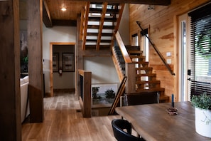 Ein Holzinnenraum mit Treppe, Essbereich und Blick durch ein Fenster.
