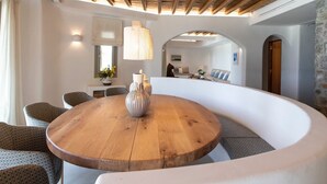 Un intérieur moderne avec un plafond en bois, une table ronde en bois agrémentée d’un vase et un banc blanc aux lignes courbes.