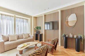 Una sala de estar moderna con sofá, sillas, una mesa de centro, televisor y un panel decorativo en la pared.