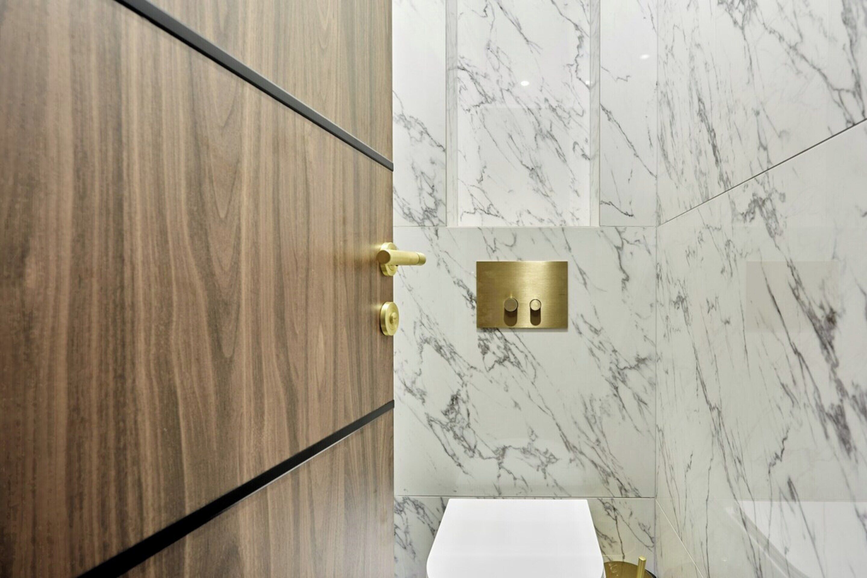 Ein Badezimmer mit Holzschrank, Marmorwänden und einem Wasserhahn aus Gold.
