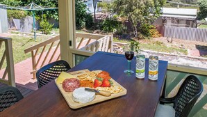 A table with a cheese platter, wine, and canisters of White Claw beer on a patio with a view of a residential area. - Moore than a Shack - Ultimate coastal retreat (Guilderton)