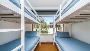 A bunk bed room with two beds, a window, and a view of a house outside. - Moore than a Shack - Ultimate coastal retreat (Guilderton)