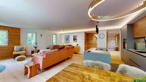 Una sala moderna con un sofá grande, piso de madera y una lámpara circular.