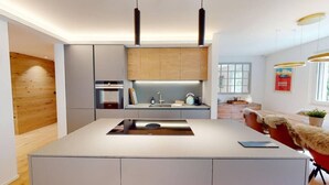 Una cocina moderna con una isla central, horno empotrado e iluminación colgante.