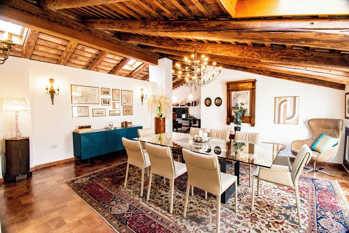 Un coin repas avec une table en verre, des chaises beiges et un tapis à motifs.