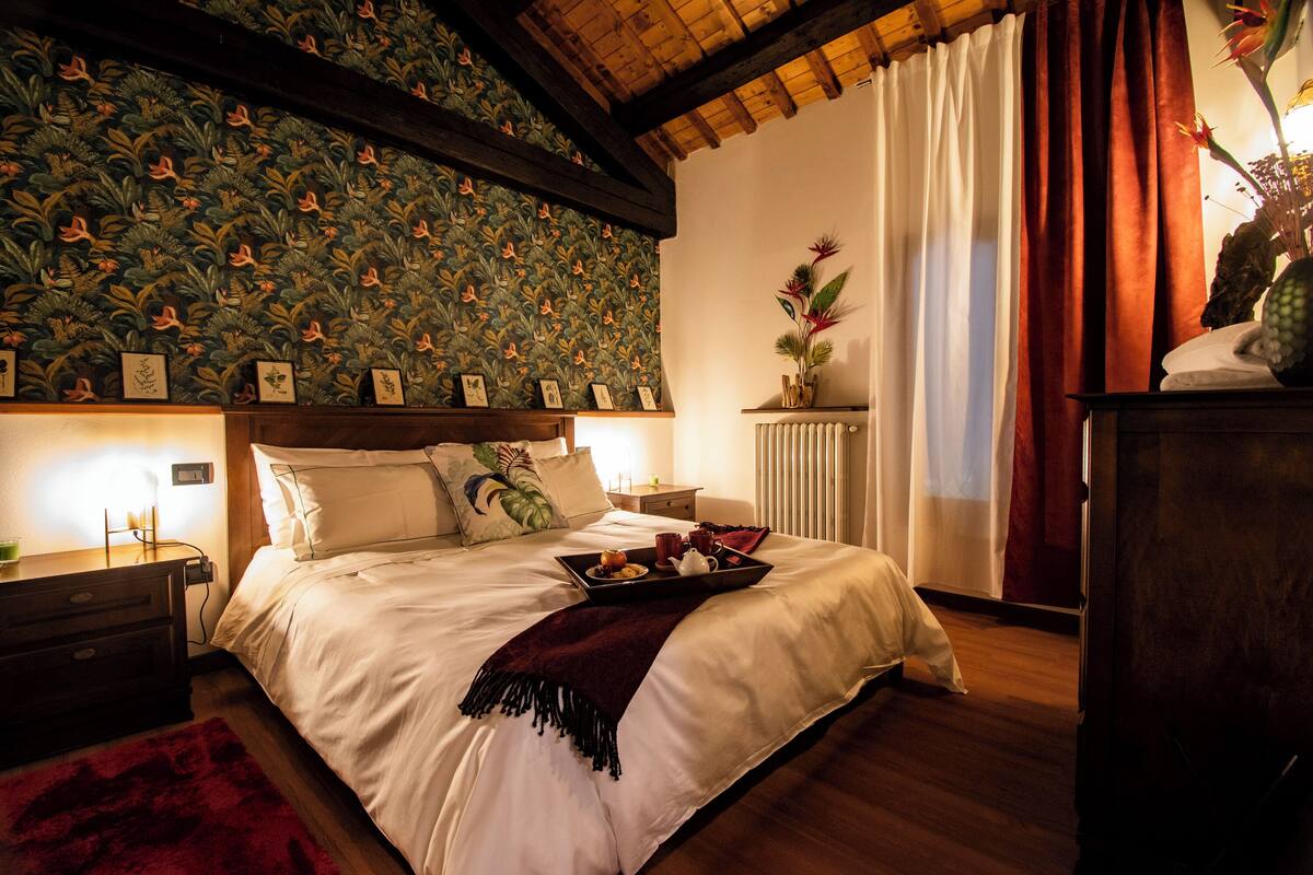 Une chambre bien éclairée, avec un grand lit, une table de chevet, une commode et un radiateur.
