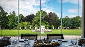 A dining table set for two with a view of a garden and a fountain. - Villa Solatia (Caldogno)