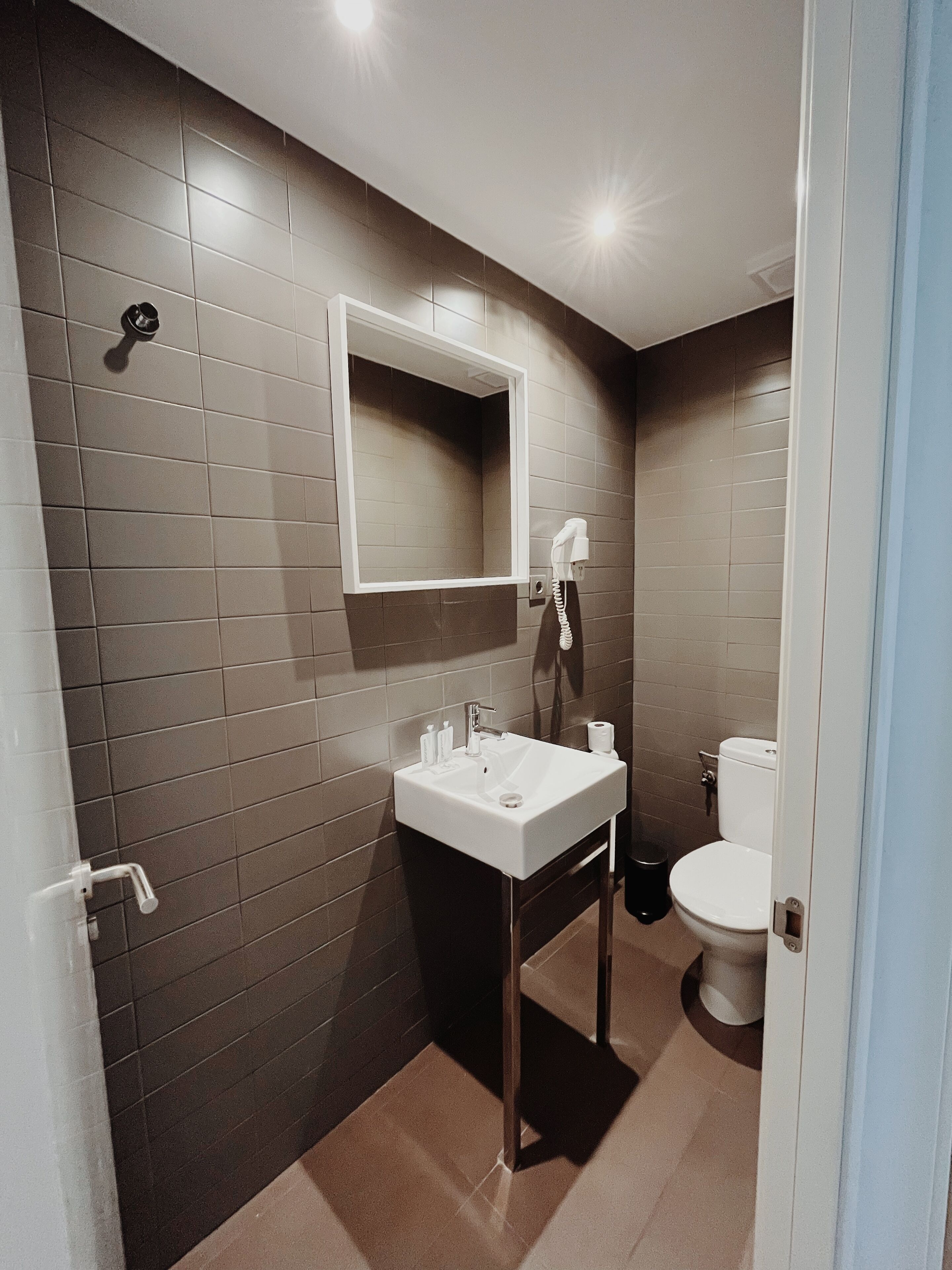 Een badkamer met een wit wastafel, een spiegel en een toilet.