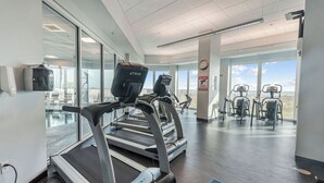 Un gimnasio con cintas de correr y máquinas elípticas, ventanas amplias y vistas al exterior.