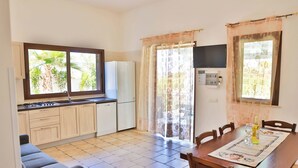 A compact kitchen with a dining area, a sofa, and a TV mounted on the wall. - Relax in Villa with Pool 150mt from the Sea 8 Beds "OA" (Alcamo Marina, Sicilia, Italia)