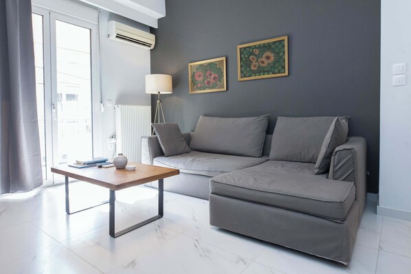 A modern living room with a grey sofa, a wooden coffee table, and two framed floral artworks on the wall.