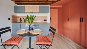 A modern kitchen with a wooden ceiling, a dining table with two chairs, and a potted plant. - Charming Studio Center of Paris-montorgueil (Paris)
