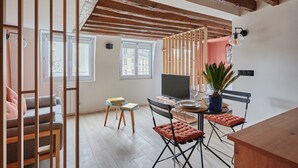 A modern living room with a wooden ceiling, a TV, a dining table with chairs, and a potted plant. - Charming Studio Center of Paris-montorgueil (Paris)