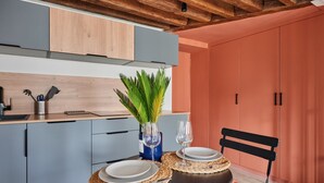 A modern kitchen with grey cabinets, a wooden ceiling, and a dining area with a round table set for two. - Charming Studio Center of Paris-montorgueil (Paris)