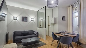A modern living room with a sofa, coffee table, and dining table set for four.