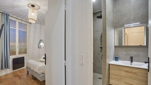 A modern bedroom with a bed, a bedside table, and a window with curtains.