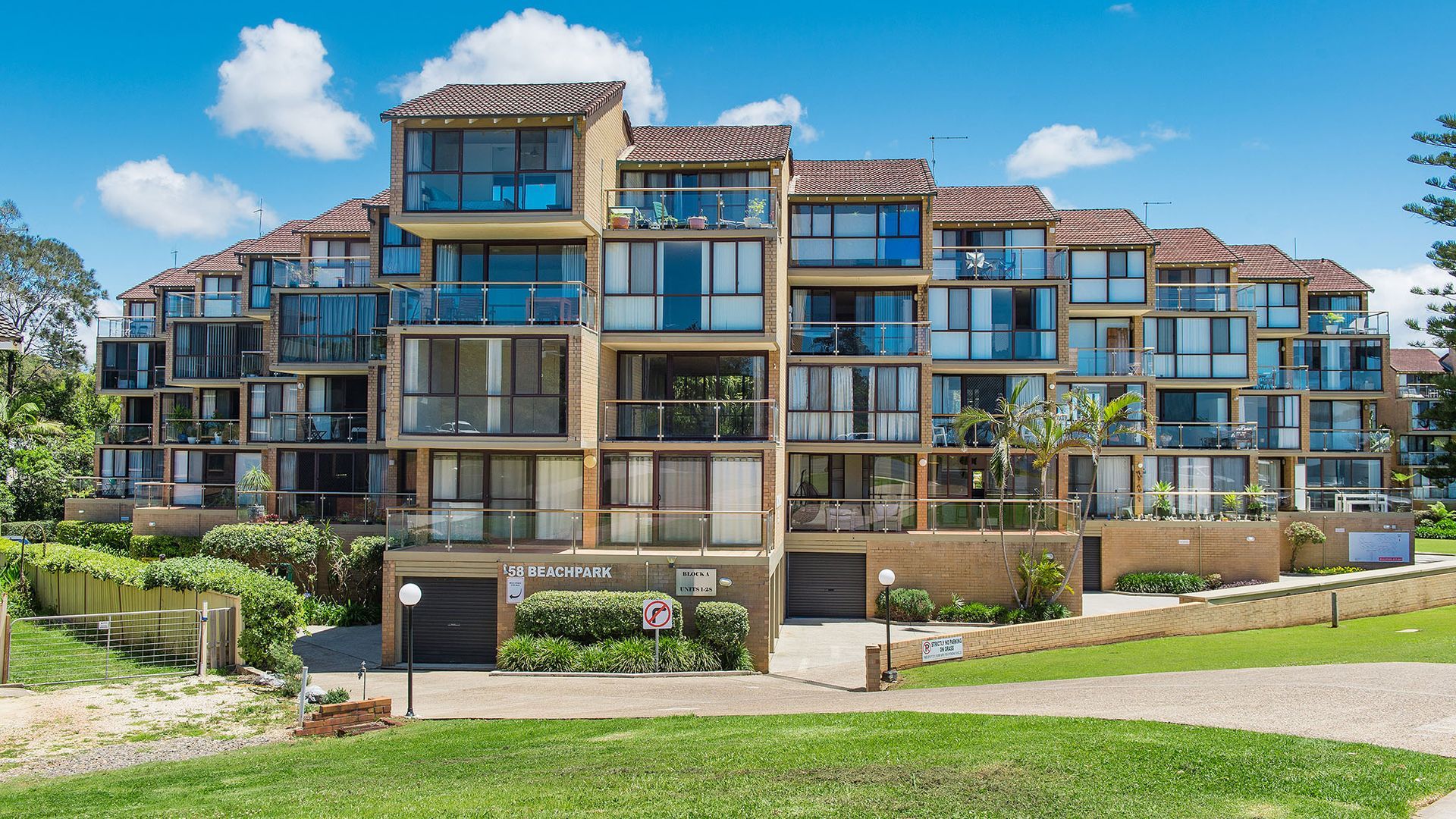 A multi-story residential building with balconies, a gated entrance, and a sign indicating '58 Beachpark.'