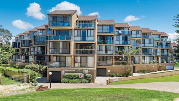 Un immeuble résidentiel à plusieurs étages, doté de balcons, d’une entrée sécurisée et d’une enseigne indiquant « 58 Beachpark ».