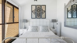 Une chambre à coucher comprenant un lit, deux tables de chevet, une fenêtre et des éléments décoratifs sur les murs.