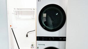 Un cuarto de lavandería con dos lavadoras apiladas de carga frontal y un tendedero.