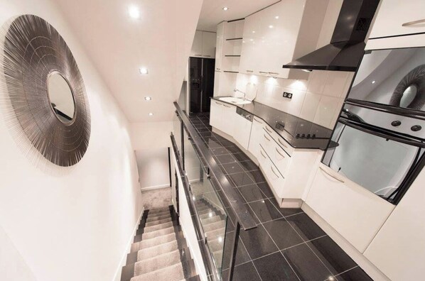 A modern kitchen with a central island, black tiled flooring, and white cabinetry.