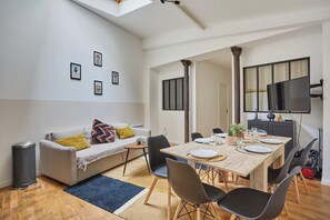 A modern living room with a dining area, featuring a sofa, coffee table, and a wooden dining table set for four.