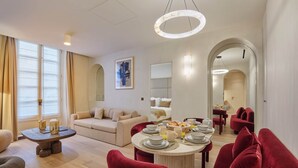 Un soggiorno moderno con zona pranzo, con un tavolo rotondo apparecchiato per la colazione, un divano e una poltrona rossa.