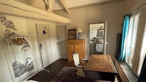 A bedroom with a bed, wooden desk, chair, wardrobe, and a window with curtains.