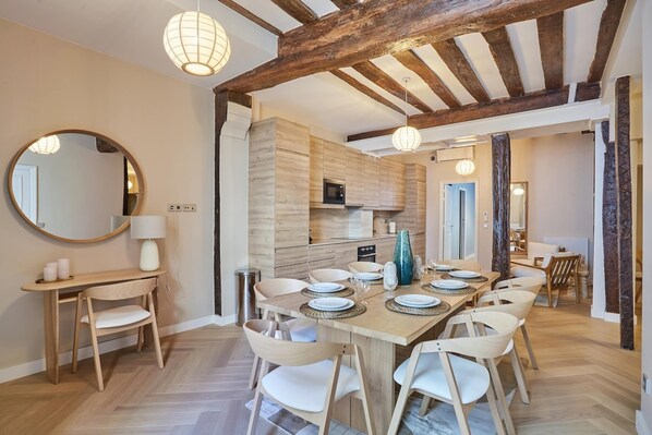 Eine moderne Küche mit Holzausbau, einem Essbereich mit großem Tisch und Stühlen sowie einem sichtbaren Mikrowellenherd.