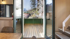 A modern interior with a wooden ceiling, a glass door leading to a balcony with a wooden floor, and a staircase to the right. - Olivia s Home in Ponte di Legno (Ponte di Legno)